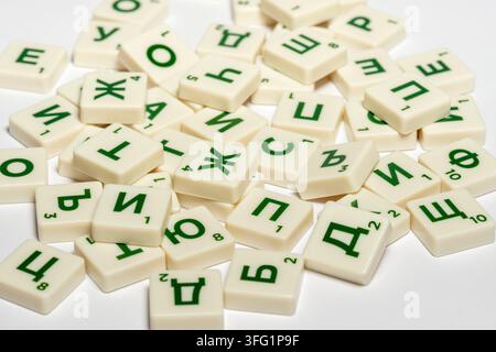 Tuiles dispersées de lettres cyrilliques avec des lettres vertes sur des pièces blanches, tuiles de jeu de société Scrabble en lettres cyrilliques bulgares Banque D'Images