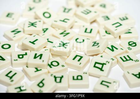 Tuiles de Scrabble dispersées avec des lettres cyrilliques en vert sur une surface blanche, tuiles de jeu de plateau Scrabble avec lettres cyrilliques bulgares Banque D'Images