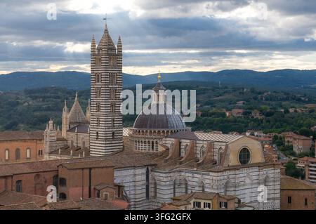Cathédrale de Sienne Duomo di Siena avec son clocher rayé et son dôme devant les collines toscanes sous un ciel nuageux dramatique. Concept pour l'héritage italien Banque D'Images