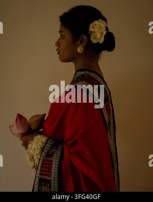 Portrait d'une femme indienne en tenue traditionnelle avec des fleurs dans les cheveux, tenant une fleur de lotus. Banque D'Images