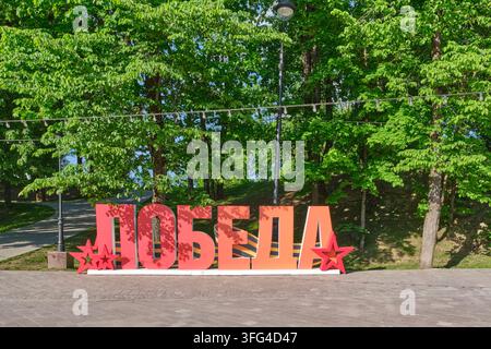 Smolensk, Russie - 19 mai 2026 : Installation festive de lettres rouges épelant Victoire en russe avec des étoiles dans le jardin Lopatinsky, célébrant la Première Guerre mondiale Banque D'Images