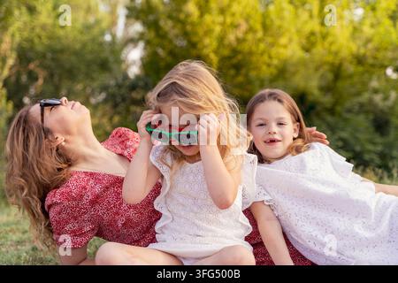 Famille se relaxant ensemble en plein air, mère et enfants partageant des moments heureux dans un parc Banque D'Images