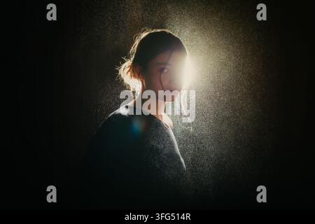 Femme regardant par-dessus son épaule dans une lumière arrière vive Banque D'Images