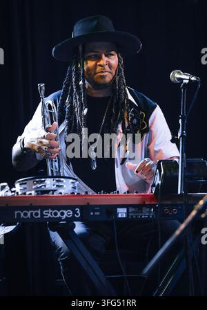 Musicien élégant avec des dreadlocks à son clavier tenant une trompette Banque D'Images