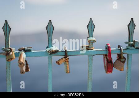 Serrures d'amour rouillées accrochées à une clôture bleue patinée à Santorini Banque D'Images