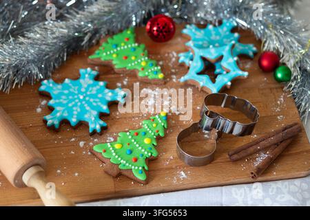 Une tasse colorée en forme de Santa tient une boisson chaude à côté de biscuits festifs en forme d'arbres et de flocons de neige. Banque D'Images