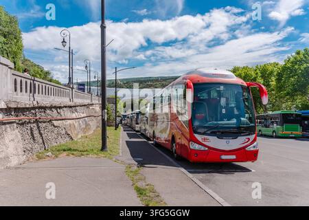 Un bus touristique à deux étages rouge vif avec arrêt à volonté circulant dans les rues du centre de Tbilissi, en Géorgie. Le bus de tourisme passe devant des bâtiments historiques Banque D'Images