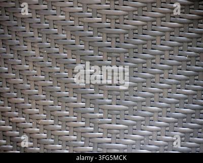 Une texture en rotin osier gris en gros plan sur la surface d'une chaise de mobilier d'extérieur en terrasse comme arrière-plan Banque D'Images