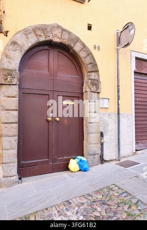 Ordures ménagères en attente de ramassage à côté d'une porte traditionnelle, adaptées au contenu sur l'assainissement urbain et les services municipaux. Banque D'Images