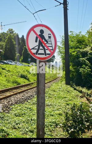 Panneau rond rouge de prohibition près de la voie ferrée interdisant aux personnes de marcher sur les voies ferrées, avertissement de zone de passage piétonne dangereuse. Banque D'Images