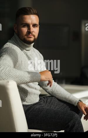 Professionnel en détente dans un espace lounge moderne, vérifiant son smartphone. Style de vie professionnel, atmosphère détendue et lumière naturelle. Banque D'Images