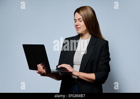 Femme d'affaires debout avec un ordinateur portable ayant une consultation en ligne ou enseignant Banque D'Images