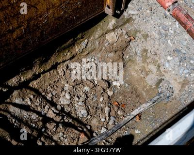 Vue rapprochée détaillée d'une excavation de tranchée profonde sur un chantier de construction, révélant le sol, le gravier et les lignes de services lors de la rénovation des infrastructures Banque D'Images