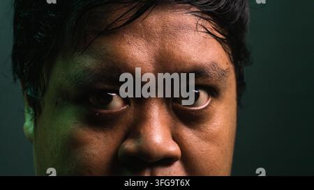 Un plan macro extrêmement rapproché se concentrant sur les yeux et le nez d'un homme asiatique adulte avec un regard extrêmement intense et perçant. Le sujet indonésien fe Banque D'Images