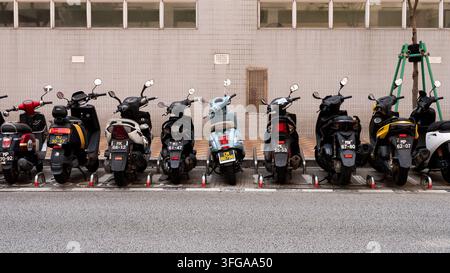 Range de scooters et de motos garés dans une rue de Macao, en Chine Banque D'Images