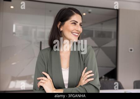 Femme experte en entreprise souriante debout les bras croisés regardant sur le côté Banque D'Images