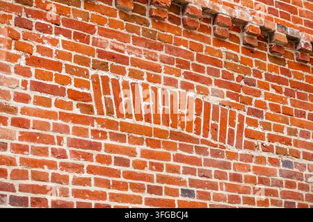 Une prise de vue en gros plan avec une perspective plate met en valeur un mur de briques rouges rustique présentant un motif décoratif diagonal d'inserts de briques sous une lumière naturelle douce. B Banque D'Images