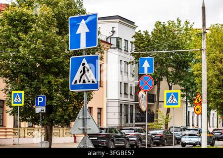 Un ensemble complexe de panneaux de signalisation routière européens comprenant un passage piéton, une rue à sens unique et une limitation de vitesse sur une route urbaine. Les voitures garées s'alignent le long Banque D'Images