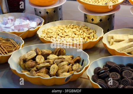 Une vue détaillée en contre-plongée d'une ligne de buffet de snacks présentant des figues séchées au centre, encadrées de bols de délicatesse turque, de bâtonnets de bretzel et de noix de cajou Banque D'Images