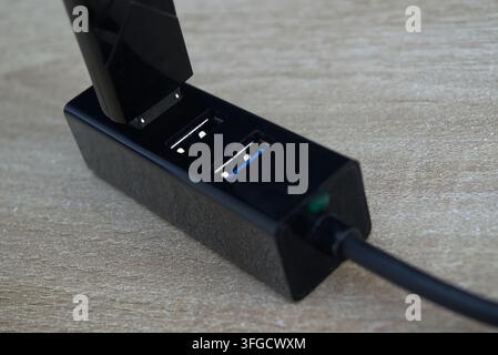 Prise de vue rapprochée détaillée d'une clé USB noire connectée à un hub USB multiport sur une surface en bois. Banque D'Images