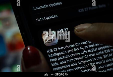 Dans cette illustration photo, une personne appuie sur le bouton „Mettre à jour maintenant“ sur un iPhone affichant l'écran de mise à jour logicielle iOS 27, mettant en avant la dernière nouveauté d'Apple Banque D'Images