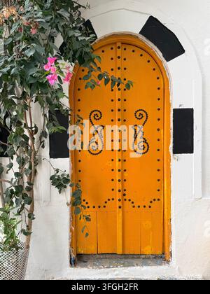 Entrée arquée orange vif encadrée par des bougainvillées dans le Medina historique de Sousse, Tunisie Banque D'Images