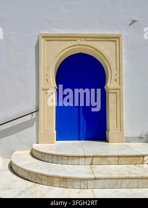 Entrée voûtée bleue traditionnelle encastrée dans un bâtiment blanchi à la chaux à Hergla, une ville côtière près de Sousse, Tunisie Banque D'Images
