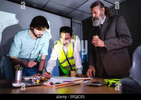 Équipe de gestion de la construction discutant du plan de bâtiment sur papier sur le bureau avec un investisseur senior en salle de réunion. Concept de planification de projet, calendrier des travaux Banque D'Images