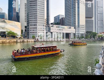 Bateau traditionnel fonctionnant comme taxi aquatique touristique sur la croisière de la rivière de Singapour naviguant devant les tours de bureaux modernes du centre-ville de Singapour Banque D'Images