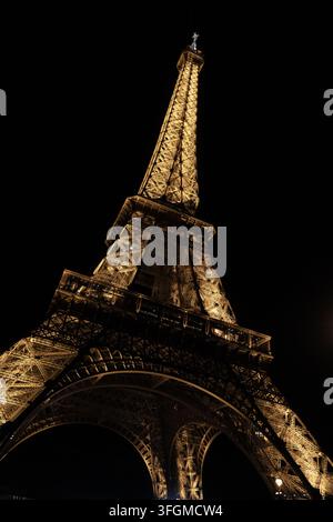 Tour Eiffel illuminée la nuit vue d'en bas contre un ciel noir à Paris, France Banque D'Images