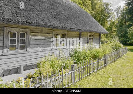 Maison en bois traditionnelle avec toit de chaume dans une campagne verdoyante. Banque D'Images
