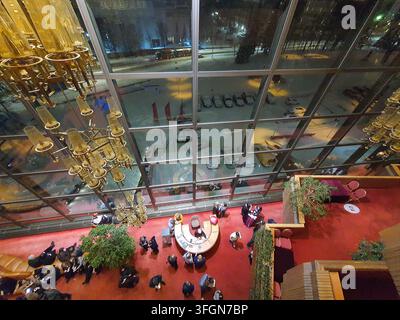 Une vue en contre-plongée d'un espace intérieur moderne et luxueux, probablement un hall d'hôtel ou un lieu haut de gamme, comportant de grandes fenêtres du sol au plafond Banque D'Images