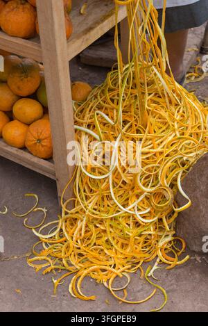 Présentation en gros plan de zeste d'agrumes vif s'échappant sur une surface en pierre, accompagné d'oranges fraîches. Un affichage vibrant de couleurs naturelles Banque D'Images