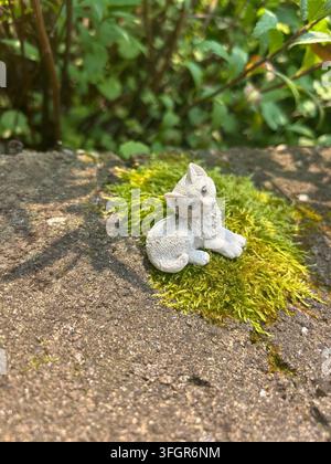 Petite figurine de chat reposant sur de la mousse dans un cadre de jardin Banque D'Images
