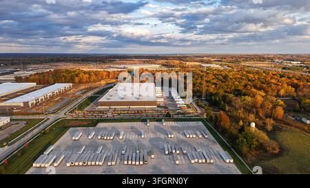 Centre de distribution avec de nombreuses semi-remorques sur un grand parking entouré d'arbres d'automne Banque D'Images