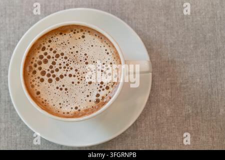 Vue de dessus d'une tasse de café fraîchement infusé avec une mousse crémeuse et des bulles, servi dans une tasse en céramique blanche Banque D'Images