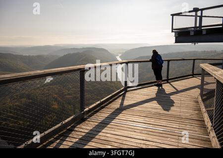 Un visiteur se tient sur une plateforme d'observation en bois surplombant le méandre de la Saarschleife au Treetop Walk Saarschleife en Sarre, Allemagne. Banque D'Images