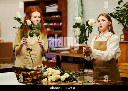 Deux fleuristes femmes arrangeant des roses dans un atelier floral Banque D'Images