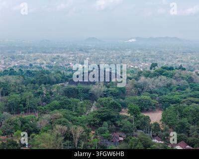 Vue aérienne du temple de Borobudur entouré d'une forêt tropicale luxuriante et de montagnes lointaines à Magelang, Jawa Tengah, Indonésie. Banque D'Images