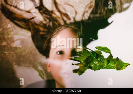 Visage de femme dans une double exposition artistique avec des feuilles Banque D'Images