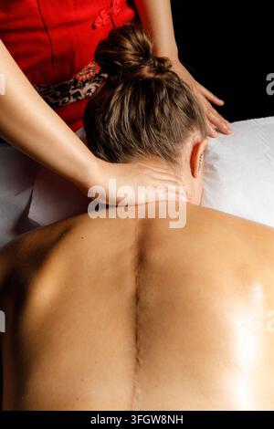 Femme avec une cicatrice chirurgicale recevant une thérapie par massage du dos Banque D'Images