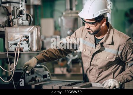 Homme indien utilisant un souffleur d'air pour le nettoyage de maintenance des déchets métalliques sur une table de fraisage dans l'industrie lourde du métal après le travail. Banque D'Images