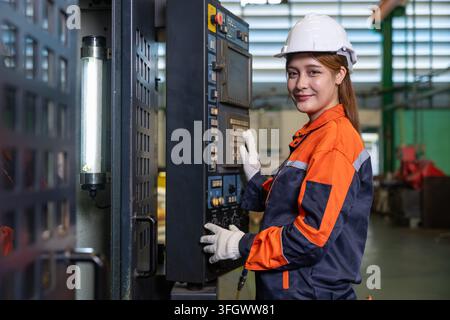 Portrait Ingénieur femme travaille opère une machine CNC en usine pendant les heures de travail en équipement de sécurité regardant la caméra heureuse souriante Banque D'Images