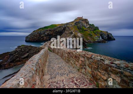 Vue de Gaztelugatxe avec son escalier de pierre sinueux et son pont menant à l'ermitage sur l'îlot rocheux entouré par la mer en Espagne. Banque D'Images
