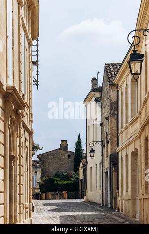 Rue pavée tranquille bordée de bâtiments en pierre et de lanternes murales ornées dans le centre historique de Saint Emilion, Nouvelle-Aquitaine, France Banque D'Images