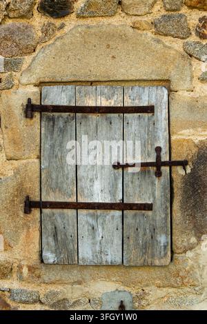 Ancienne fenêtre en bois fermée dans un mur de maison en pierre, Auvergne, France Banque D'Images