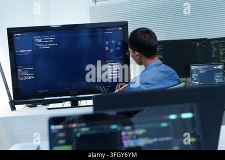 Développeur logiciel analysant le code source, les interfaces numériques et les visualisations de données connectées tout en développant des applications avancées de cyberespace et d'intelligence artificielle. Banque D'Images