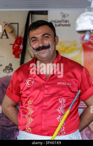 Homme turc joyeux en uniforme rouge traditionnel vendant de l'authentique glace dondurma en plein air dans la station balnéaire de Side. Banque D'Images