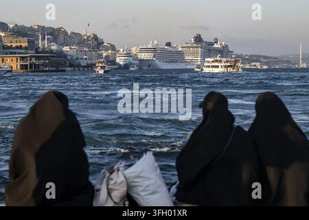 Vue de trois femmes portant des abayas noires regardant le Bosphore avec des navires de croisière et la ligne de ville en arrière-plan à Istanbul, Istanbul Banque D'Images