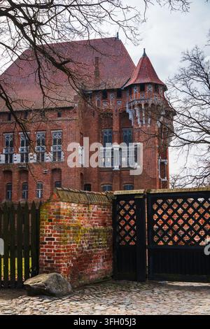 Malbork, Pologne – 23 mars 2026 : Vue du château de Malbork avec son architecture emblématique en briques rouges, ses fenêtres gothiques ornées et un mur historique en briques dans le Banque D'Images